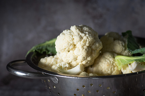 Fresh organic cauliflower in a large metal pot, ready to cook in rustic gray background.Close up.