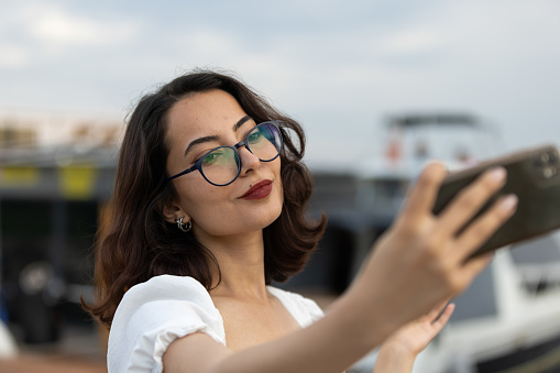 brunette woman is taking a photo with mobile phone for her social media account.