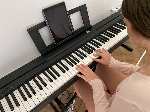 Teen girl playing electric piano in her room