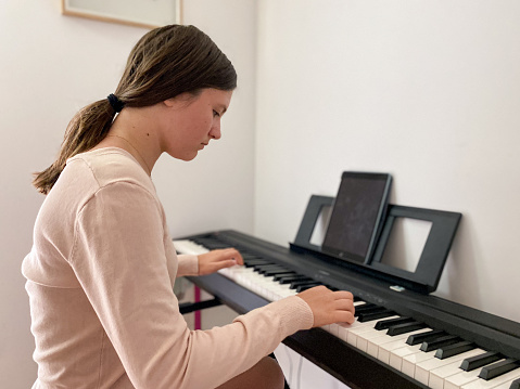 Teen girl playing electric piano in her room