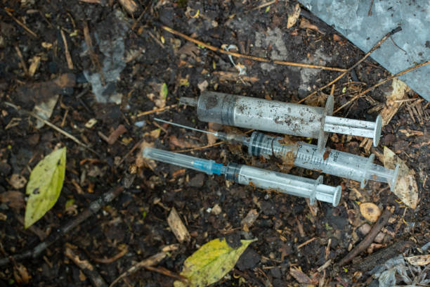 bunch of used dirty syringe leaved after drug injection lying on ground outdoor - shooting up imagens e fotografias de stock