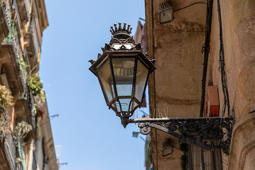 Barcelona, Spain - June 22, 2023: Narrow alley in Barcelona Gothic Quarter, Catalonia, Spain. Old lantern on the facade of a building