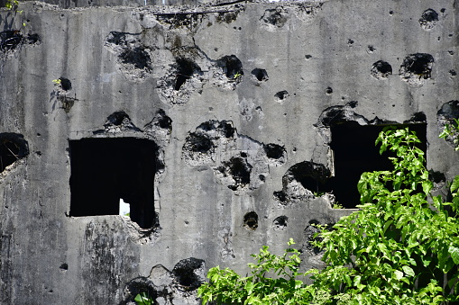 Yelch, Airai State, Babeldaob Island, Palau: battle damage on concrete wall - impact holes of small and large calibre weapons - Japanese Communications Center ruins, Kaigun Sho.