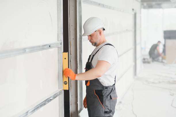 istock Man holding level against plasterboard, interior drywall. Attic renovation 1511845019