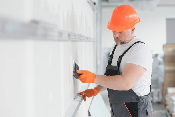 istock man drywall worker or plasterer putting mesh tape for plasterboard on a wall using a spatula and plaster. Wearing white hardhat, work gloves and safety glasses. Image with copy space. 1511845535