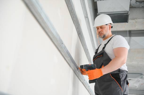 istock man drywall worker or plasterer putting mesh tape for plasterboard on a wall using a spatula and plaster. Wearing white hardhat, work gloves and safety glasses. Image with copy space. 1511852539