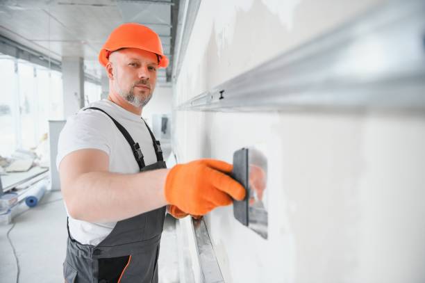 istock man drywall worker or plasterer putting mesh tape for plasterboard on a wall using a spatula and plaster. Wearing white hardhat, work gloves and safety glasses. Image with copy space. 1511858245