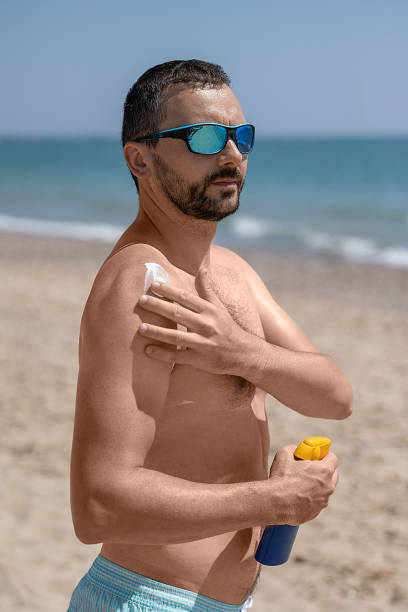 istock A young white man in sunglasses with a beard applying sunscreen. 1511859843