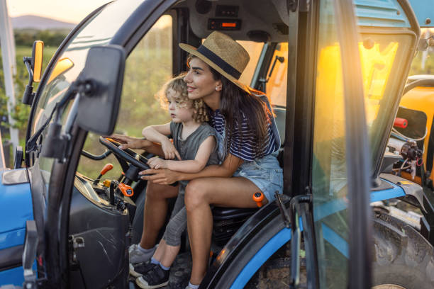 Woman and her son are observing a green tractor in a field near lake bohinj, slovenia, during their summer vacation