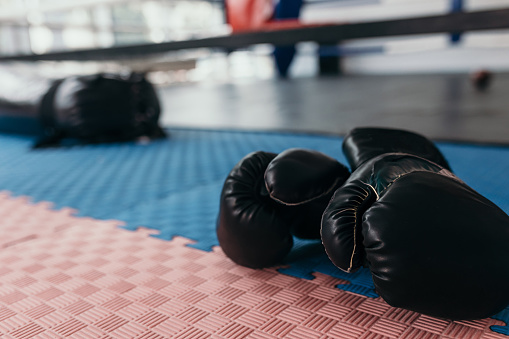 Close up of boxing gloves with boxing ring in the background
