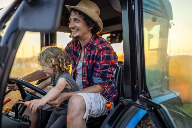 istock Farmer dad with his boy in tractor at farm 1511904477