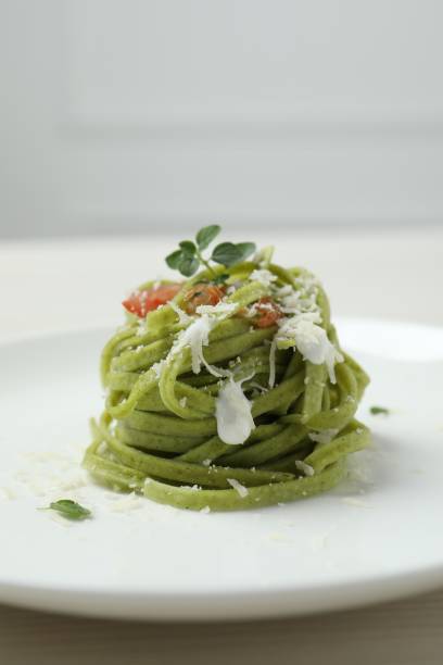Tasty tagliatelle with spinach and cheese on plate, closeup. Exquisite presentation of pasta dish