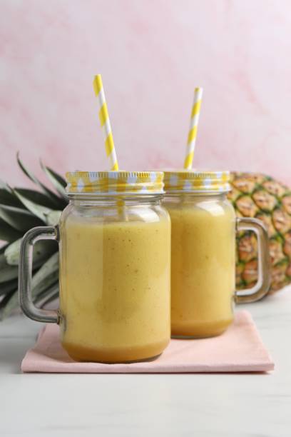 istock Tasty pineapple smoothie and fruit on white table 1511916494