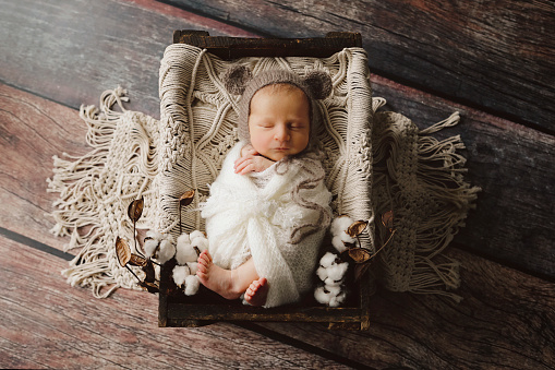 An image of a newborn baby boy, thirteen days new, wearing a bonnet with bear ears.