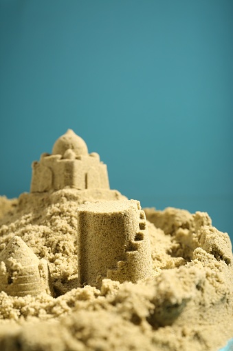 Pile of sand with beautiful castle on light blue background. Space for text