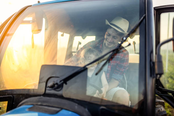 istock Farmer dad with his boy in tractor at farm 1511923026