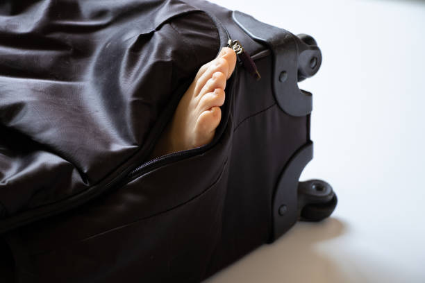 woman's leg sticking out of a suitcase, human trafficking, slave trade, transporting people to sell organs - black market color image photography kidnapping imagens e fotografias de stock