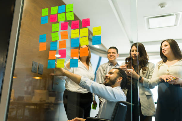 istock Disabled businessman pointing at sticky notes and brainstorming with co-workers 1511925808