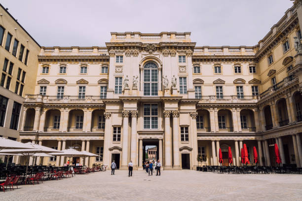 Berlin, Germany - June 1, 2025: Humboldt Forum in the reconstructed Berlin Palace, featuring intricate architectural details, outdoor seating areas, and visitors in a bustling courtyard.