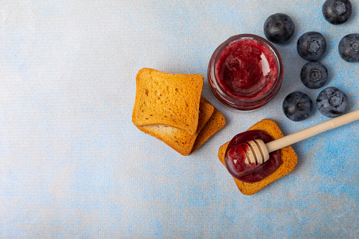 Toasted bread toast with jam. A jar of raspberry jam. Delicious toast with sweet jam served for breakfast on the table. Delicious toasts on a textured background. Space for text. Place for copying.