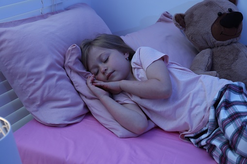 A cute little girl fast asleep in a double bed