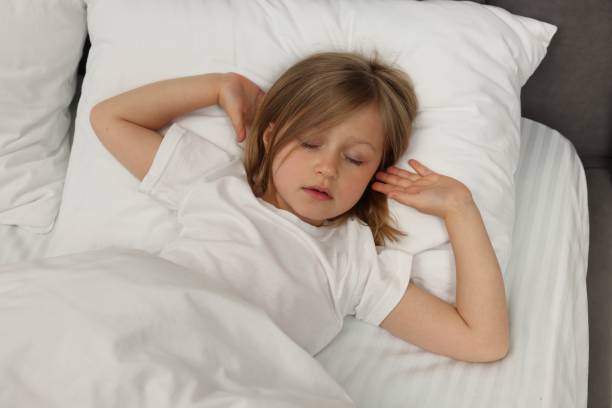 istock Little girl snoring while sleeping in bed, above view 1511950337