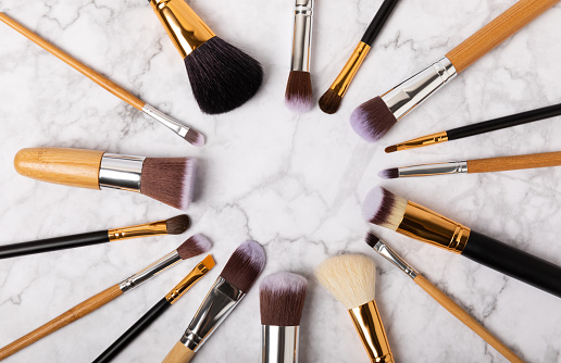 Cosmetic product for makeup. Makeup brushes on a white marble background. Creative fashion concept. Collection of cosmetic makeup brushes, top view, banner.Flat lay.