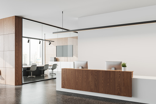 Interior of modern office with white walls, concrete floor and white and wooden reception desk with two computers. 3d rendering