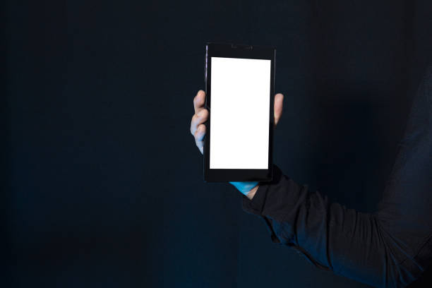 istock Business man showing a small vertical tablet with blank screen isolated on a dark background. Streaming and technology concept. 1512046328