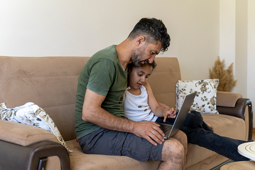 Father and daughter working together on laptop at home