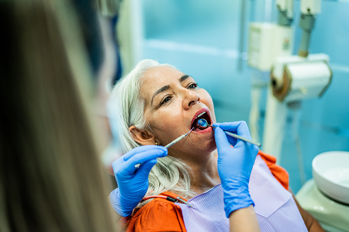 Mature woman having teeth examined by a dentist at her office