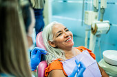 Mature woman having teeth examined by a dentist at her office