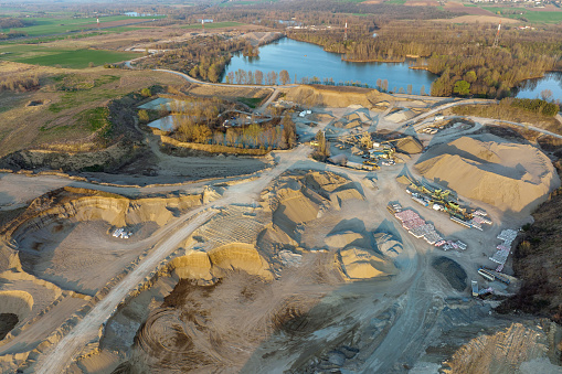 Aerial view of open pit mining of limestone materials for construction industry with excavators and dump trucks.