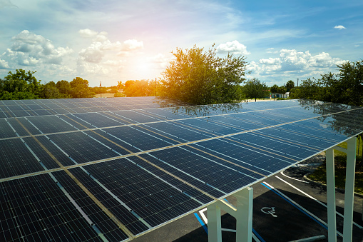 Aerial view of solar panels installed as shade roof over parking lot for parked cars for effective generation of clean electricity. Photovoltaic technology integrated in urban infrastructure.