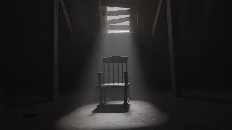 old rocking chair illuminated by light ray at dark attic. Concept age and past