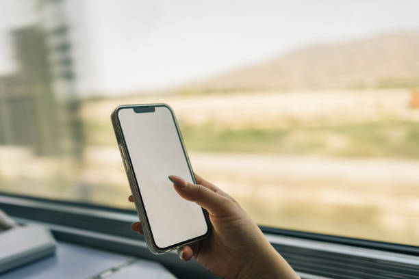 istock Woman's hand holding mobile phone on a high speed train ride. Unrecognizable young girl using phone technology while traveling on high speed train for leisure or business. 1512138078