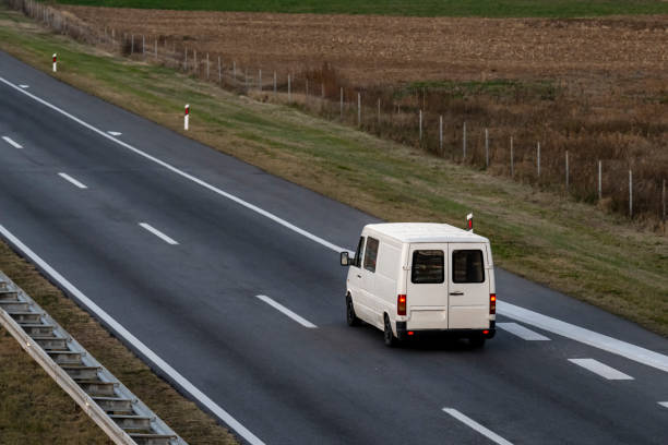 white delivery van on the highway. white modern delivery small shipment cargo courier van moving fast on motorway road to city urban suburb. the world's best transport of goods. - van moving van commercial land vehicle truck imagens e fotografias de stock