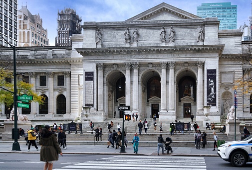 New York, NY - November 17, 2021:  Busy street scene with pedestrians walking in front of the New York Public Library building on Fifth Avenue
