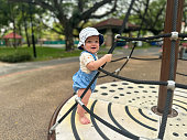 Young baby boy stands on the playground smiling