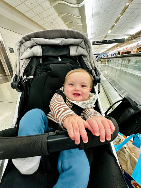 istock Baby boy smiles while being pushed in a stroller at the airport 1512242225