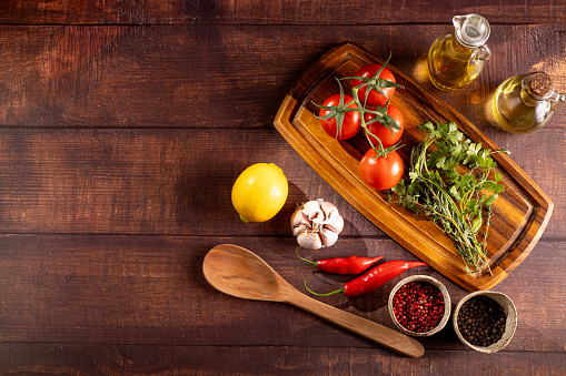 Ingredients for cooking on the table. Tomatoes, peppers, garlic, herbs, oil and spices.