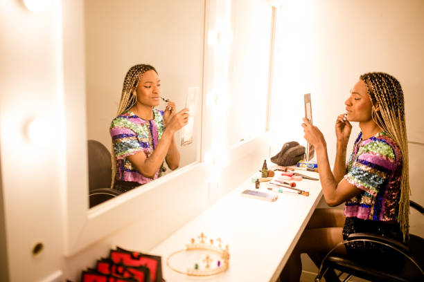 Frau trägt Lippenstift auf. Frau trägt Lippenstift auf, sitzt in der Umkleidekabine vor dem Spiegel. Lippenstift-Make-up-Archivbilder, lizenzfreie Fotos und Bilder
