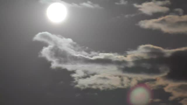 Time-lapse of the night sky with the moon. Bright moon in dark night sky. Timelapse of passing clouds in night sky.