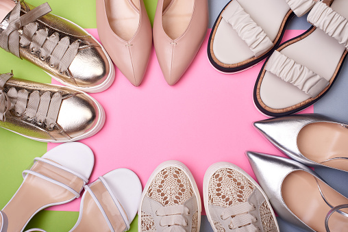 Variety of stylish summer women's shoes on the color background. Flat lay, top view, copy space on center. A modern and fashionable shoe store.
