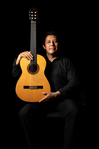hispanic classical guitarist guitar player on a black background, studio shot portrait