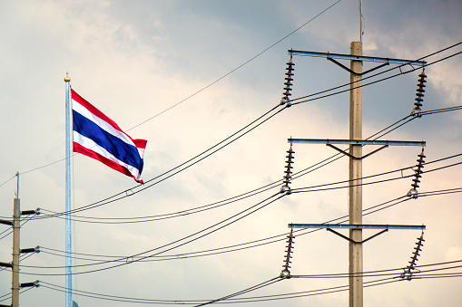 Thai flag and electricity power lines over cloudy sky in Bangkok