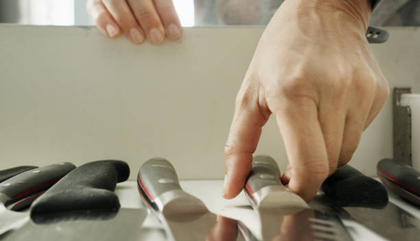 Close-up of a woman's hands picking up a knife from kitchen drawer