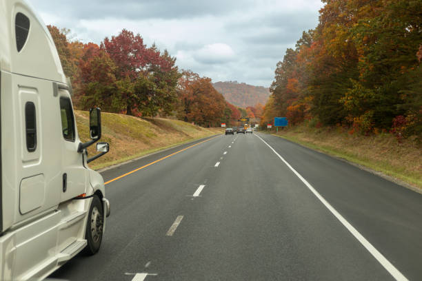 istock truck is driving down a road with trees in the background. 1512437665