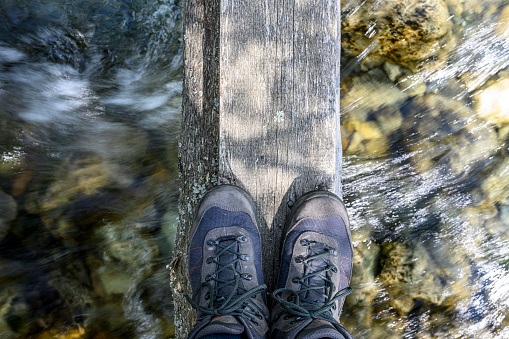 Standing in hiking boots on a tree trunk above a river