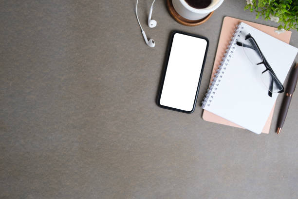 istock Smart phone with blank screen, notebook, coffee cup and earphones on grey background. Top view with copy space. 1512531219